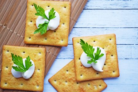 Delicious crackers with cheese sauce and vegetables.Snack on wooden background.の写真素材