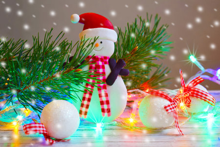 Christmas card.Pine branch and snowman on wooden background.Glowing lights.の写真素材