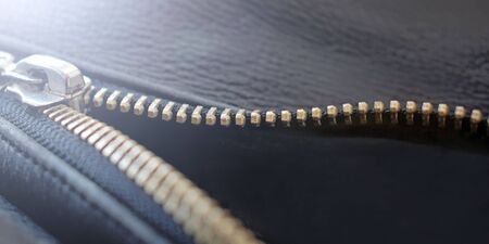 Macro shot of zipper on black leather texture background with stitching. Horizontal background from...