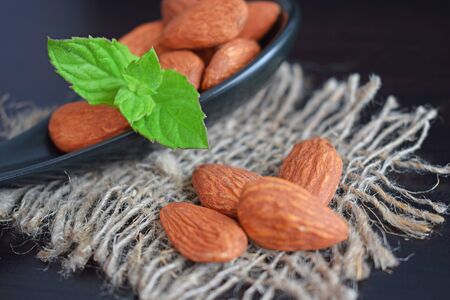 Delicious and healthy almonds. Nuts and a sprig of mint in a spoon on a black background. Healthy diet.の写真素材