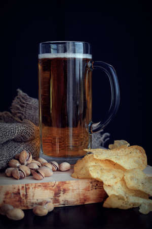 A mug of fresh beer and pistachios on a black background.の写真素材