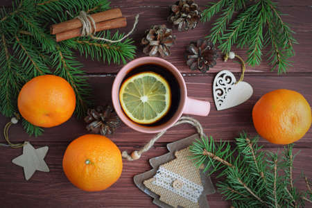 Fragrant tea, fir branches and tangerines on a wooden background. Happy winter holidays.の写真素材
