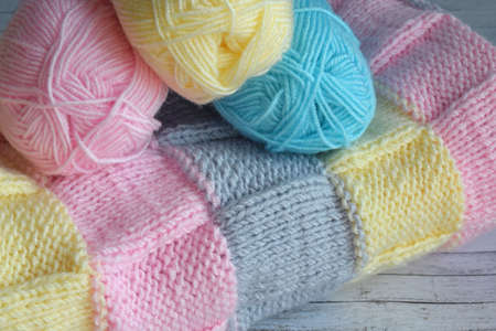 Yarn and knitted fabric on a wooden background.