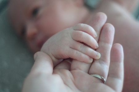 Newborn babys holding mothers finger. Mom and babyの写真素材