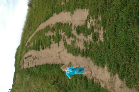 A barefoot boy in blue clothes is climbing a mountain along a country roadの写真素材