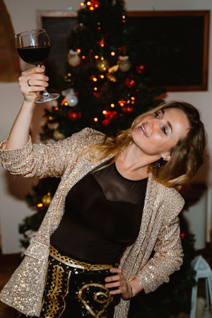 Young woman with a glass of red wine with background of a decorated Christmas tree with a burning garland. New Year or Christmas Partyの写真素材