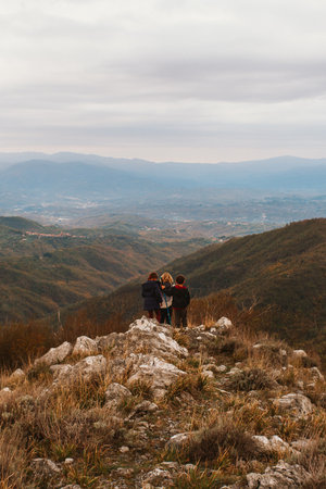 Three small unrecognizable children stand on the top of a mountain enjoying the mountain scenery. Hiking and active healthy lifestyle. Adventure holidays with childrenの写真素材