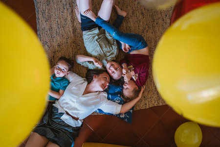 Happy mother and her three children are lying down on the floor making time for family funの写真素材