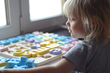 Little girl enthusiastically plays with colorful wooden alphabet letters. Concept: preschool education in a playful way.の写真素材