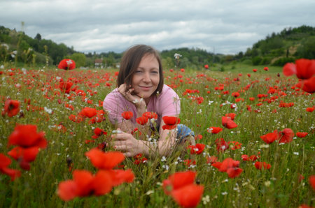 Beautiful young woman in a blooming poppy field.の写真素材