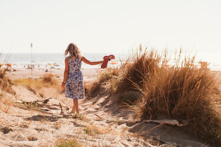 Bambina walks to sea along path among sand dunesの写真素材