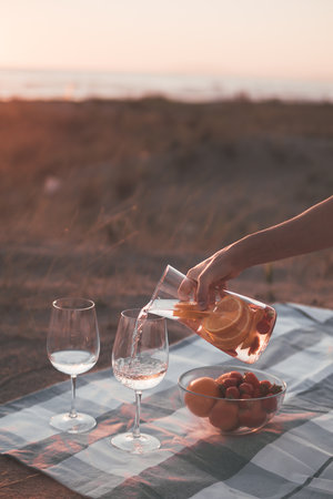 Preparing for a romantic picnic on the seashore with glasses of wine and fruits on the seashore on a...