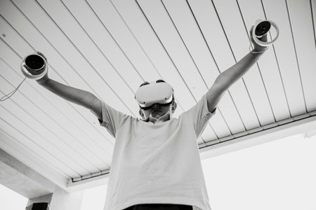 Teenager using VR glasses exploring augmented reality, using smart devices, controllers in hands....