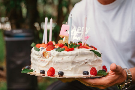 Holding a Strawberry and Berry Birthday Cake with Candles