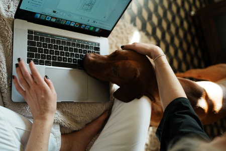 Young woman with her dog working remotelyの写真素材