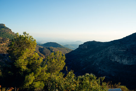 Serene landscape view of mountainous terrain with lush greenery and clear sky. Layers of hills in the distance create a peaceful and tranquil natural sceneryの写真素材