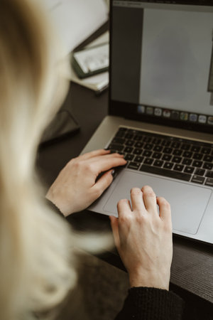 Hands of a person typing on a laptop keyboard, focusing on their work in a home office setting. Image captures a moment of digital interaction, productivity, and technology useの写真素材