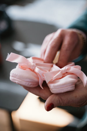Small pink baby shoes with bows being gently held in hands. The delicate shoes symbolize new beginnings, tenderness, and the excitement of welcoming a newborn into the family.の写真素材
