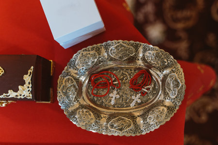 Silver tray displaying small crosses on red cords, traditional items used in an Orthodox baptism ceremony. This symbolic setup is essential for the sacred ritualの写真素材
