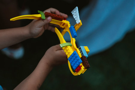 Hands of a child assembling a colorful toy structure with interlocking blocks, showcasing creativity...