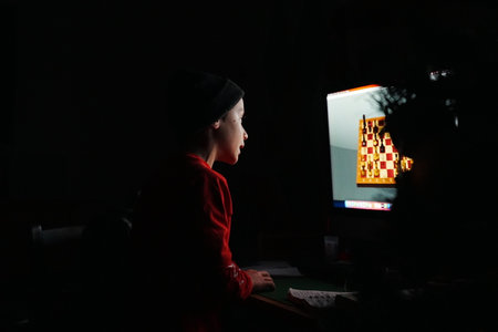 Young Boy Engages with Computer Chess Gameの写真素材