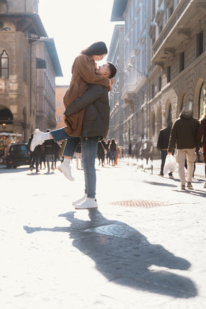 Joyful moment captured as a couple shares an emotional embrace in a lively city street. The scene conveys warmth and affection amidst bustling urban life on a sunlit dayの写真素材