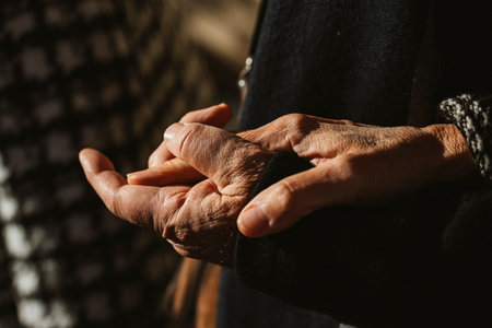 Elderly couple gently holding hands, symbolizing deep connection and enduring love. Their intertwined hands highlight warmth, comfort, and emotional support in a simple yet profound momentの写真素材
