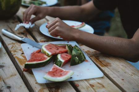 Slicing Watermelon on Wooden Table with Cutting Boardの写真素材