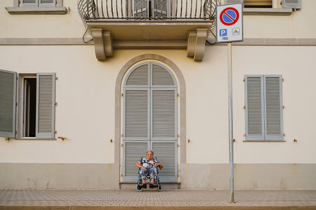 Elderly Woman Relaxing in Wheelchair by Buildingの写真素材