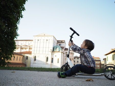 Child Learning to Ride Scooter in Urban Settingの写真素材
