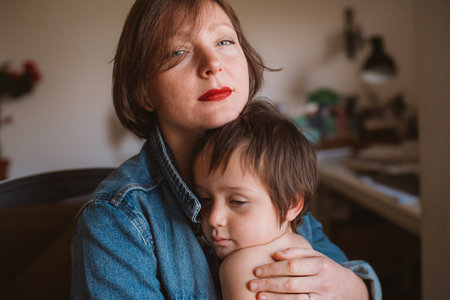 Mother and son share a tender embrace, capturing a moment of warmth and connection in a home setting. Their expressions reflect comfort and a deep emotional bondの写真素材