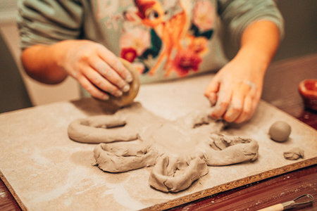 Young child immersed in sculpting clay, shaping various figures on a table. Hands actively mold the material, showing a creative process and tactile engagement.の写真素材
