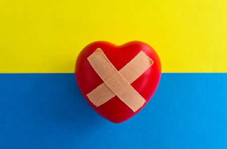 Wounded heart on background of Ukrainian flag. Russia war against Ukraine. Volunteering and helping Ukrainians conceptの写真素材