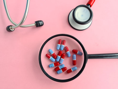 Magnifier with medical pills and red stethoscope. Search and selection of medicines for the treatment of diseases conceptの写真素材