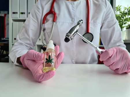 General practitioner holds jar of cbd oil and neurological hammer in hand. Medical products from cannabisの写真素材