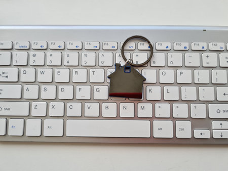 Keychain with house on computer keyboard. Booking rent searching and buying accommodation on the...