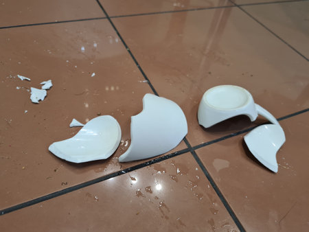 Broken white ceramic mug on floor closeup. broken dishes