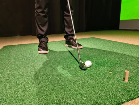 Male golfer plays golf indoors on golf simulator closeup. Driving range with screen