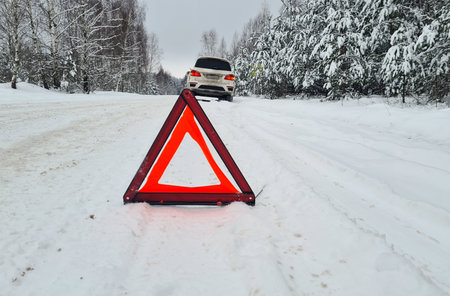 Emergency red sign on a snowy road. Car breakdown on the highwayの写真素材