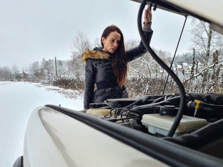 Woman checks problem with car engine. Help concept for car breakdown in winter
