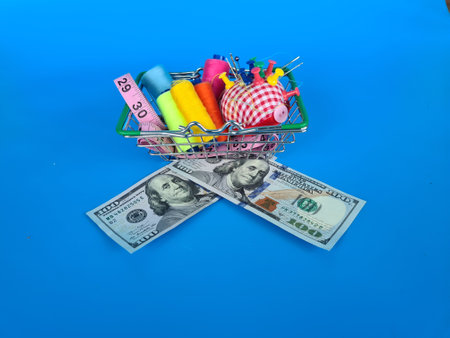 Lots of all colors of threa , needles, shopping basket and dollars. Cost of sewing accessories sewing accessories and moneyの写真素材