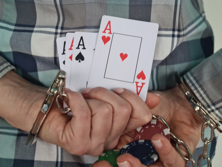 Handcuffed hands with playing cards and casino chips. Arrest poker and casino gamesの写真素材