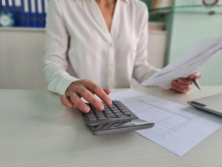 Woman using calculator and calculating bills at home office. financial expenses income and budgetの写真素材
