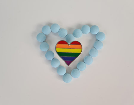 Hormonal pills after sex change. LGBT rainbow pride badge and pills on blue background
