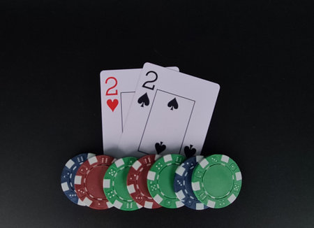 Two poker deuces on black table with chips on black background. Casino and gambling games