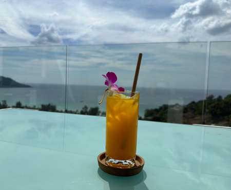 Tropical cocktail of gin and yellow passion fruit and flower on sea beach. summer cocktail