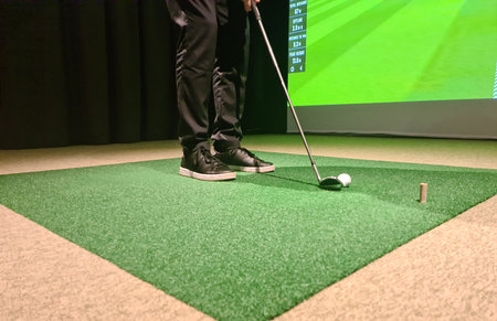 Man is playing golf on golf simulator and getting ready to hit. Screen means information about swing and range of impactの写真素材