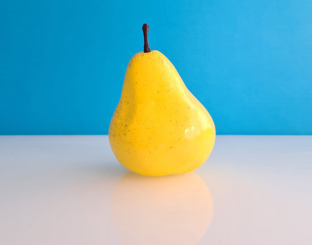Ripe beautiful yellow artificial pear on blue background. Fruits and healthy food conceptの写真素材