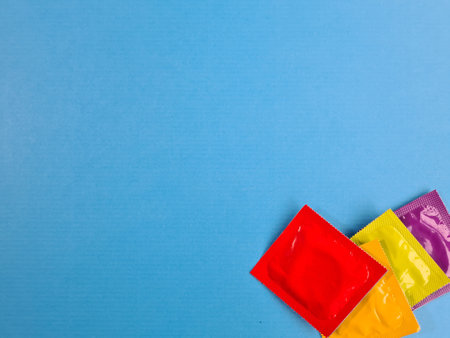Multicolored condoms on blue background. Advertising means of contraception conceptの写真素材