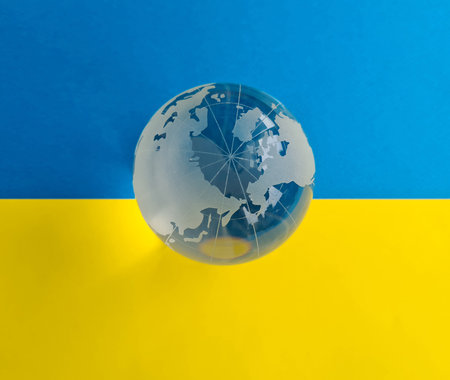 Glass world globe on background of Ukrainian flag. Peacetime and Ukraine's victory in war conceptの写真素材